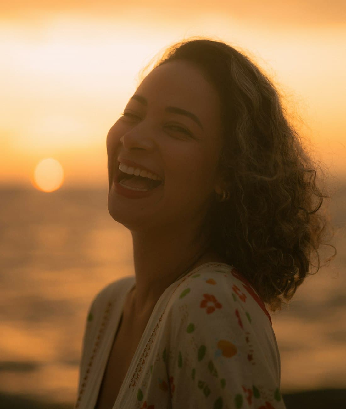 Une femme éclate de rire en écoutant sa chanson, au coucher du soleil